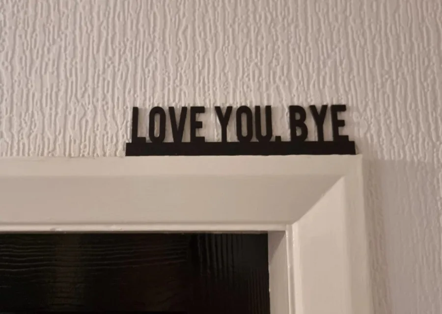 The Quirky Gift Co 'Love You Bye' personalised door topper hung over a door frame.
