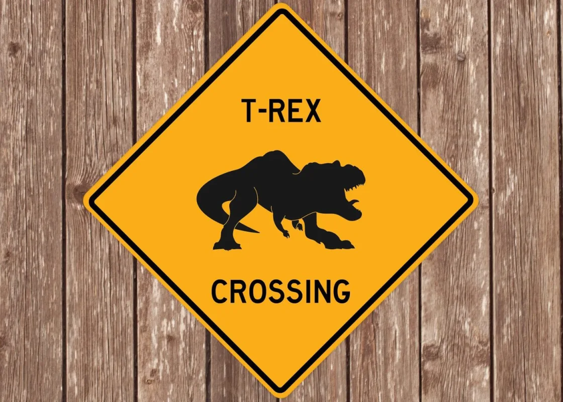 A Quirky Gift Co 'T-Rex Crossing' warning-style novelty sign.